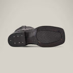 The bottom view of the Alligatoar Horn Back Print Black - Square Toe boot highlights textured leather craftsmanship. Its rectangular sole has a ribbed grip with metal studs on the heel, enhancing its sleek style against a plain light grey background.