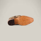 The Roxanne Crystals Tabaco boot lies on its side, displaying a sole with floral patterns and a logo. Its tall shaft and snip toe design stand out, while the dark brown heel with visible nails adds to its luxurious women’s style.